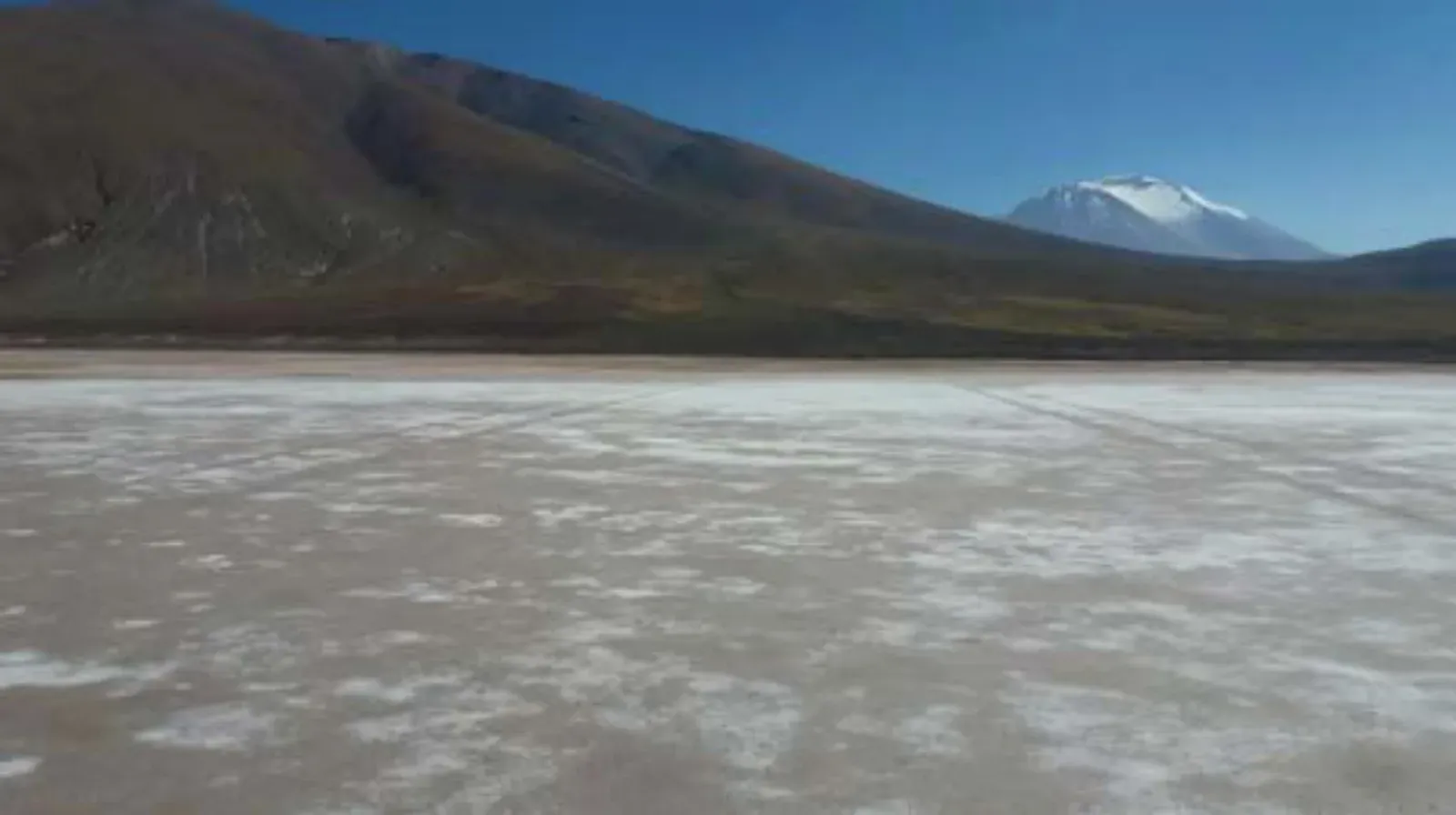 Superficie blanca del Salar de Llamara con volcán al fondo